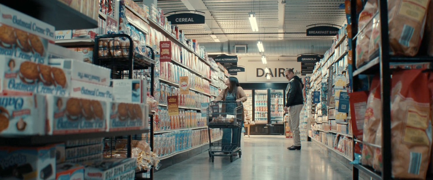 Alexei and a woman in the cereal aisle of a grocery store.