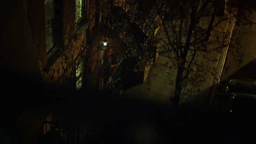 Rafi having a liaison in front of an apartment door at night.