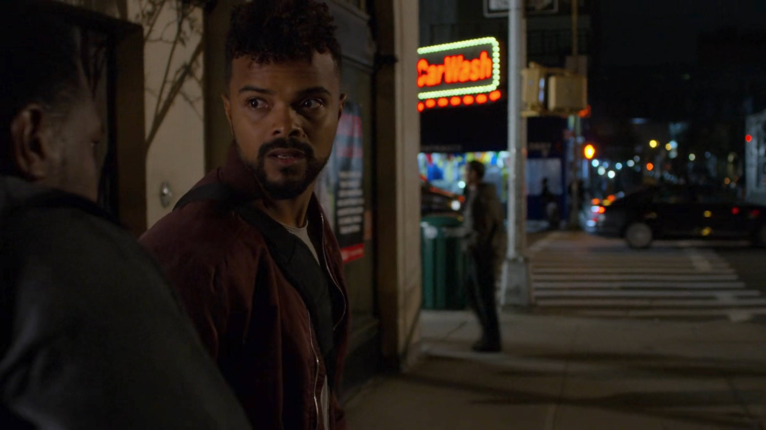 Malcolm talks to a paparazzo outside Trish's apartment building.