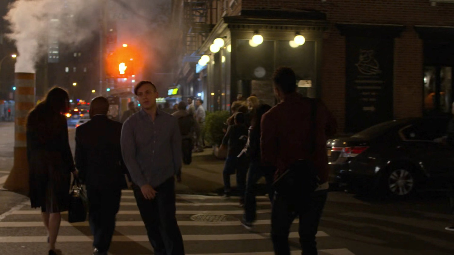 Malcolm crossing the street outside Trish's apartment building.