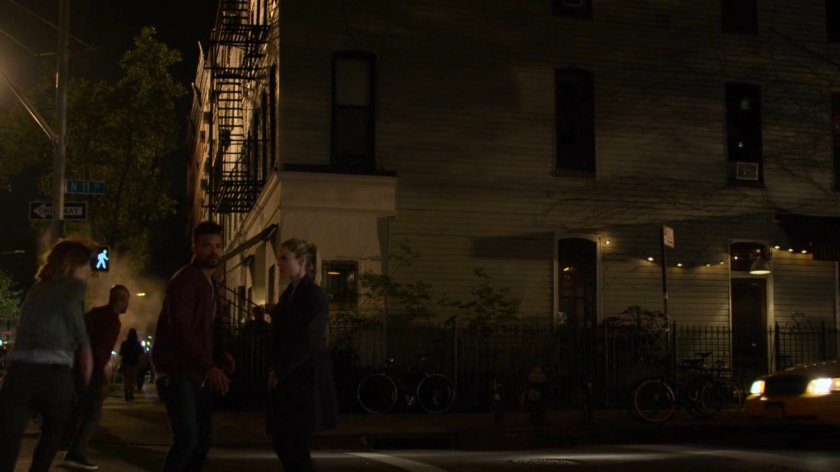 Malcolm and Trish on sidewalk outside dark bar.