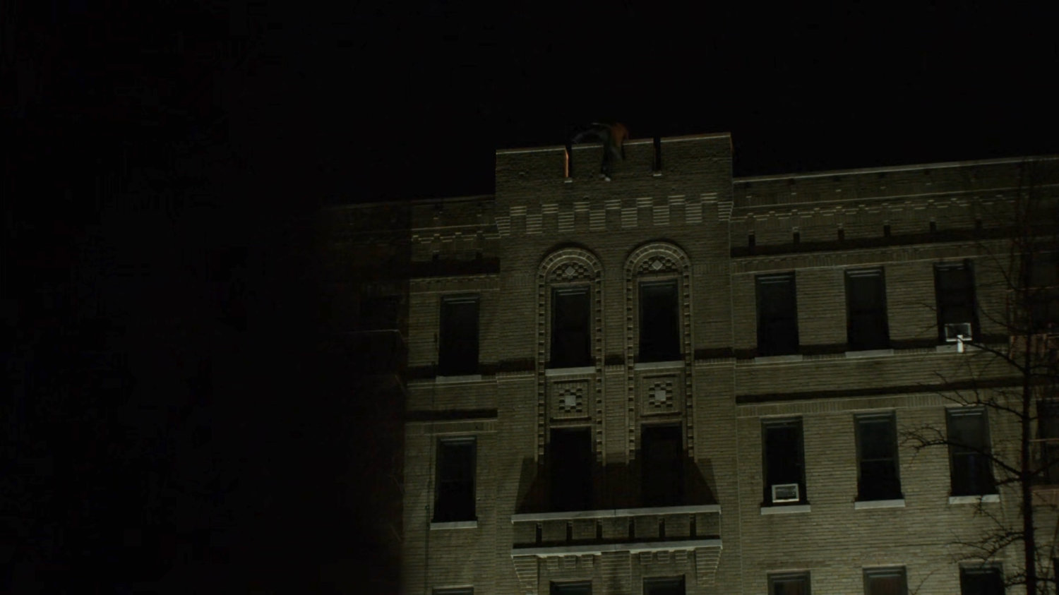 Alisa climbs over the top ledge of a building.