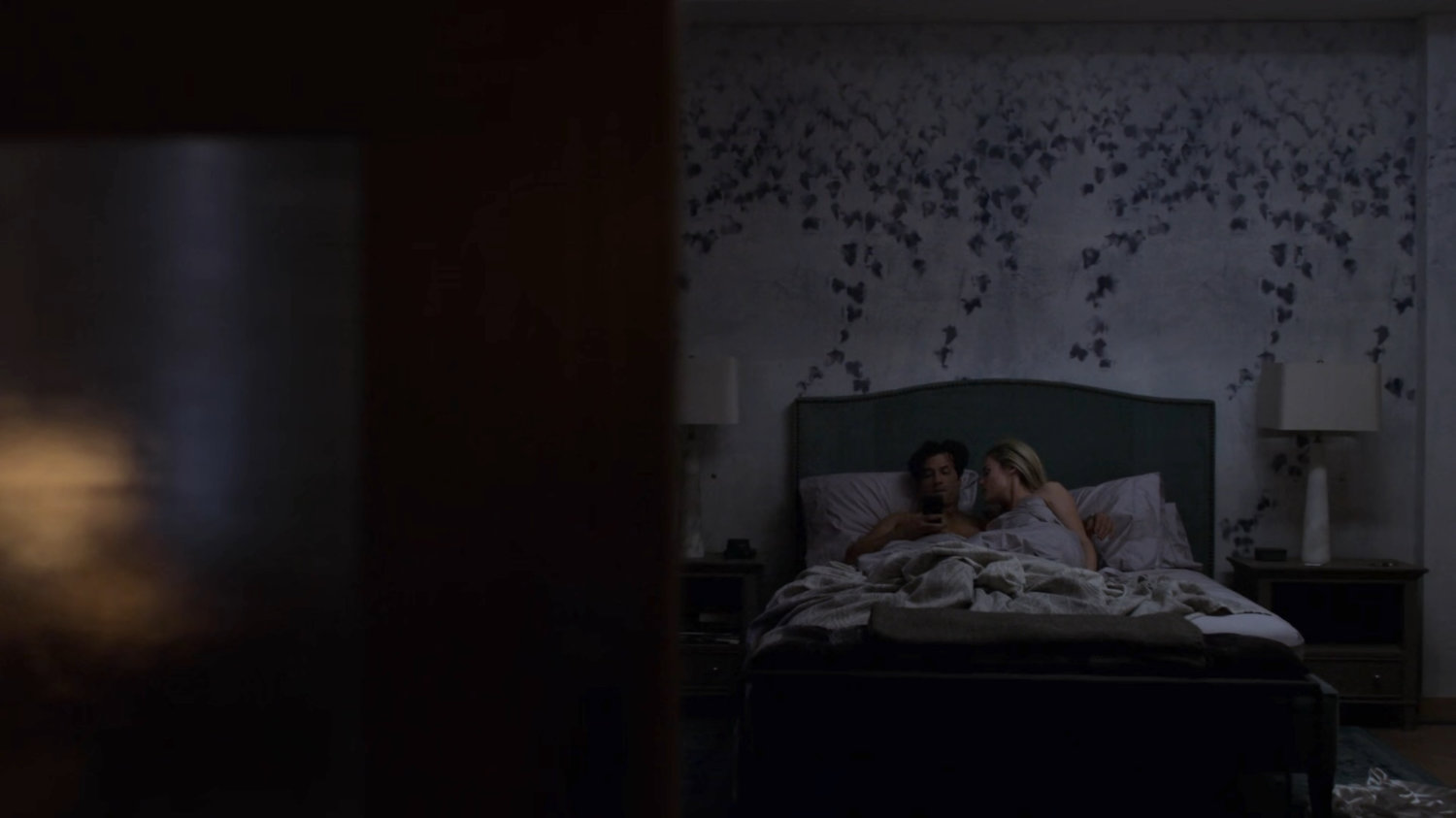 Trish and Griffin in a bed in her apartment.
