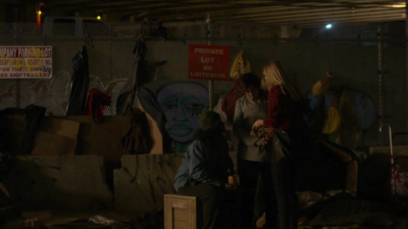 Trish asking questions at a homeless encampment at night.
