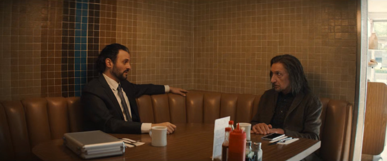 Agent Cleary and Trevor in a booth at a diner.