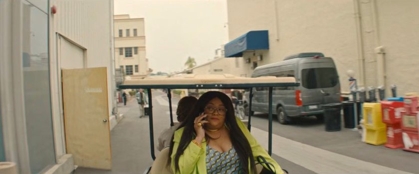 Janelle on a cell phone while riding in a golf cart around a Hollywood backlot.