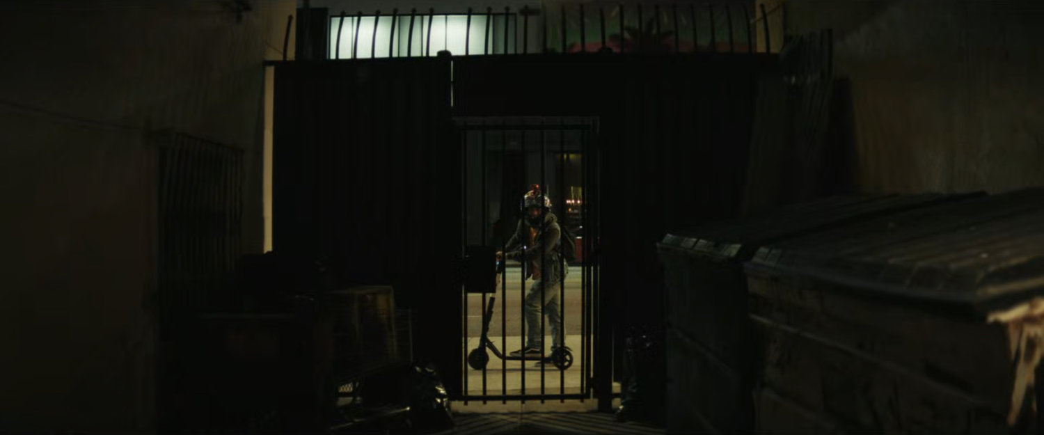 Jayden watching the fight through the gate of the alley.