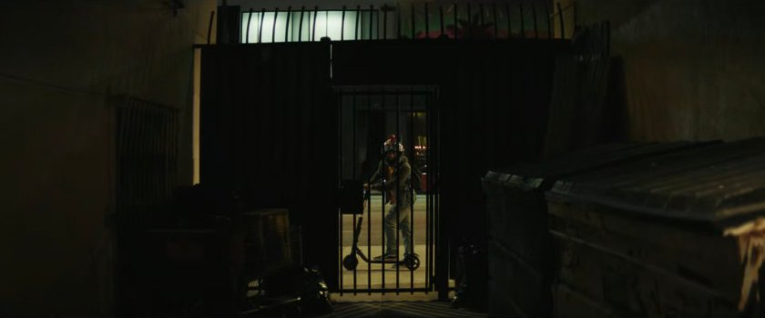 Jayden watching the fight through the gate of the alley.