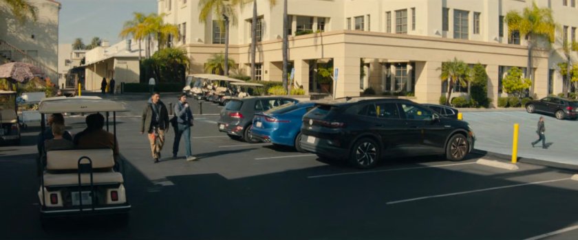 Simon and Kathy driving away in a golf cart on a studio backlot.