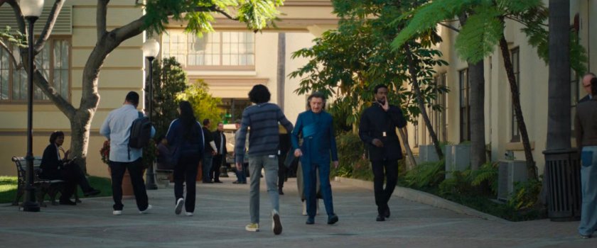 Trevor and Simon walk across a studio backlot.