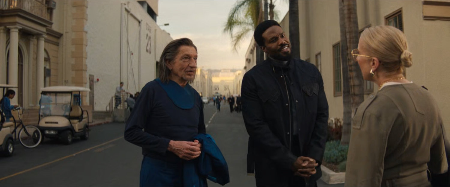 Trevor, Simon, and Kathy talk on a studio backlot.