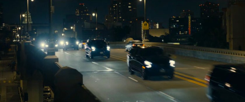 DODC SUVs race across a street bridge.