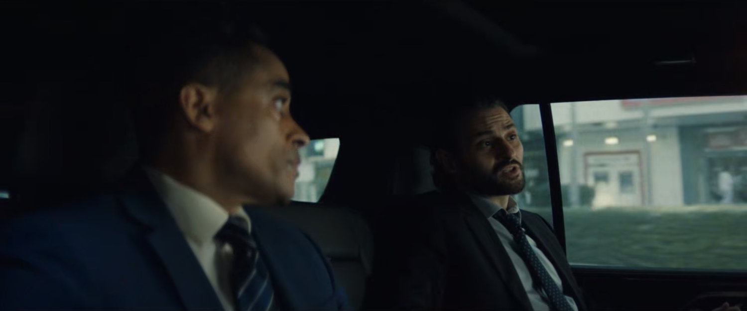Agents Marco and Cleary inside a DODC SUV driving along the street.