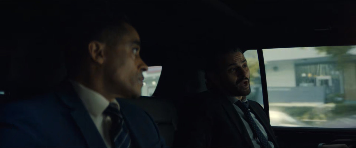 Agents Marco and Cleary inside a DODC SUV driving along the street.