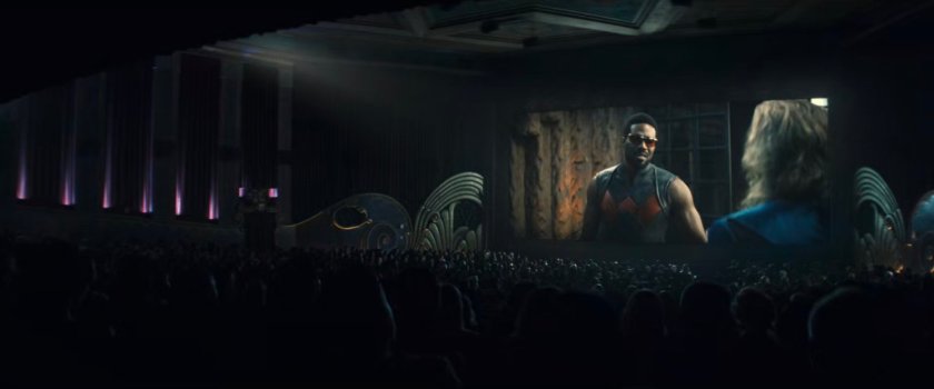 Interior of movie theater showing scene with Simon as Wonder Man.