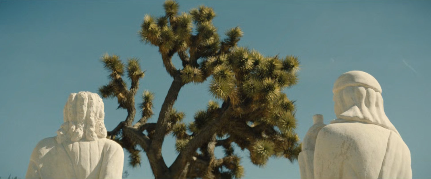 White statuary by a Joshua Tree.
