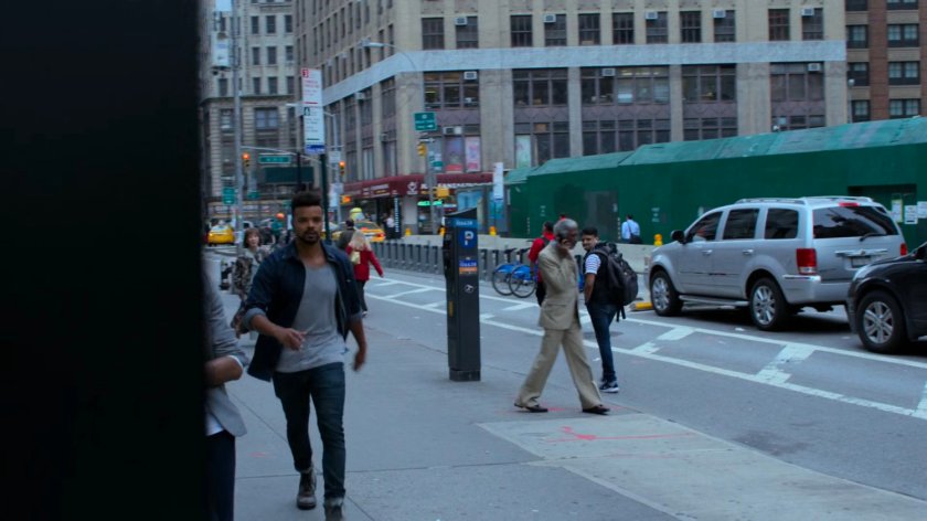 Malcolm walking along a sidewalk outside a jewelry store.