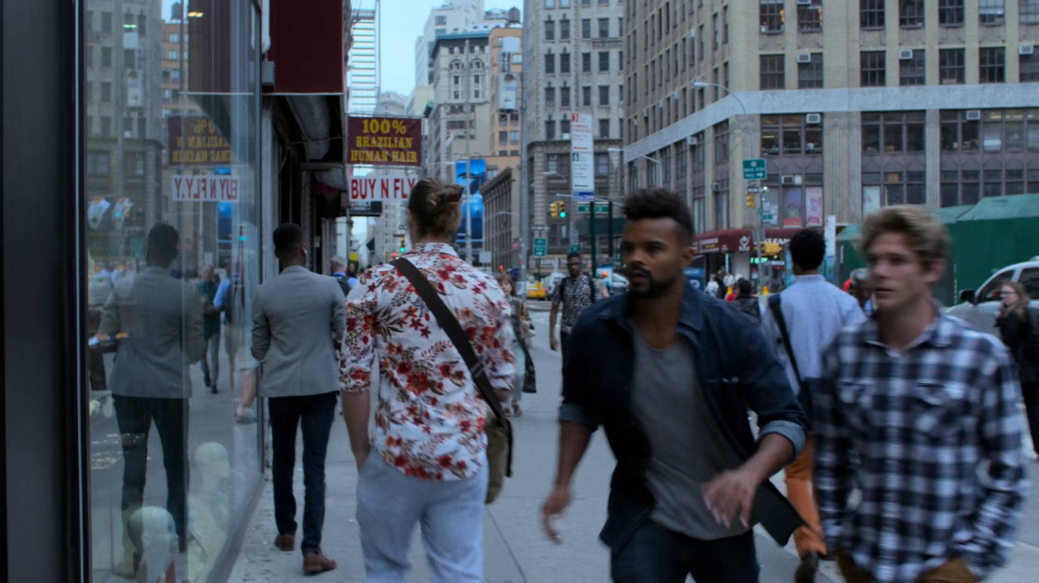 Malcolm walking along a sidewalk outside a jewelry store.