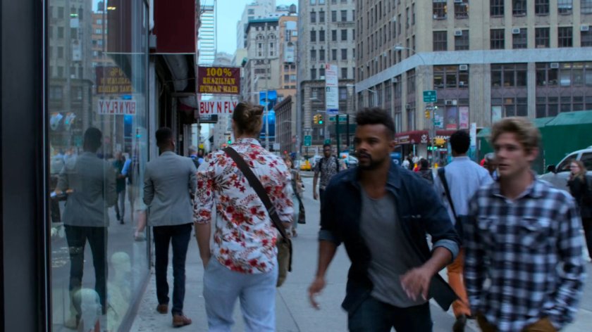 Malcolm walking along a sidewalk outside a jewelry store.