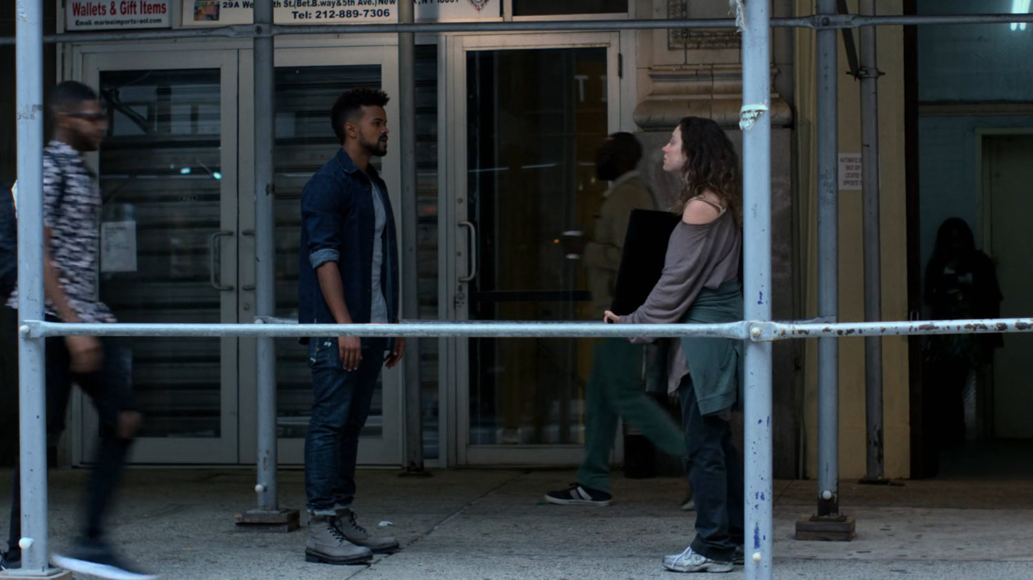 Malcolm confronting Inez outside a shop.
