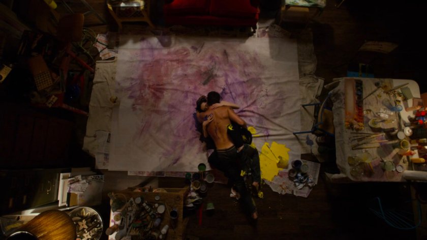 Jessica and Oscar rolling on a painted canvas in his apartment.