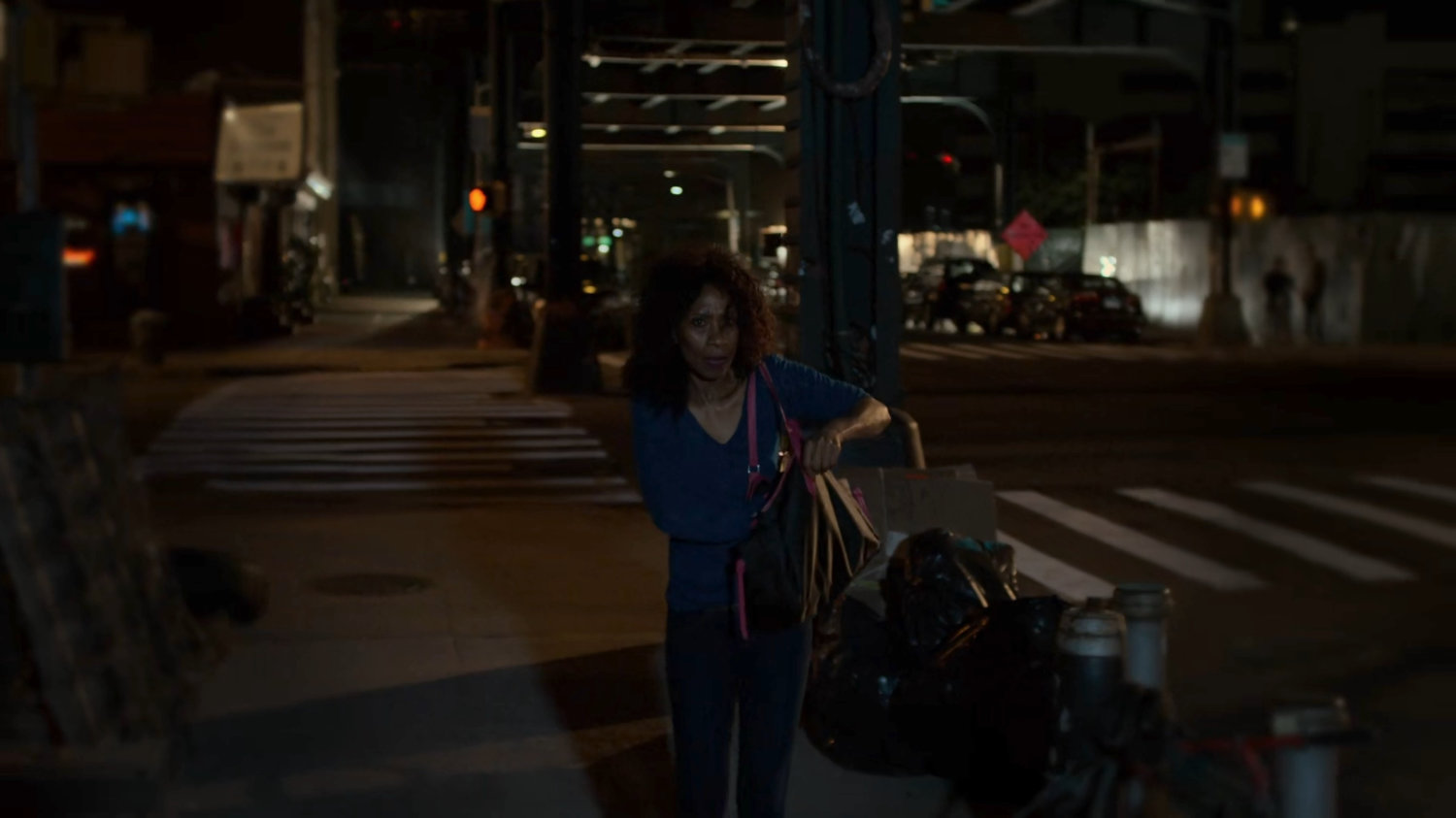 A woman walking on a dark sidewalk.