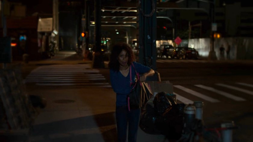 A woman walking on a dark sidewalk.