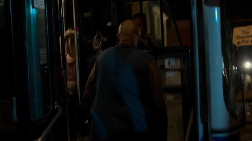 A man stepping onto a bus at night.
