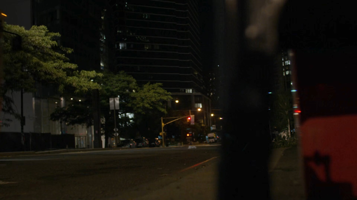 A dark sidewalk by a bus stop.
