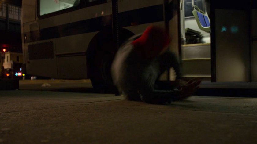 A man thrown off a bus onto the sidewalk at night.