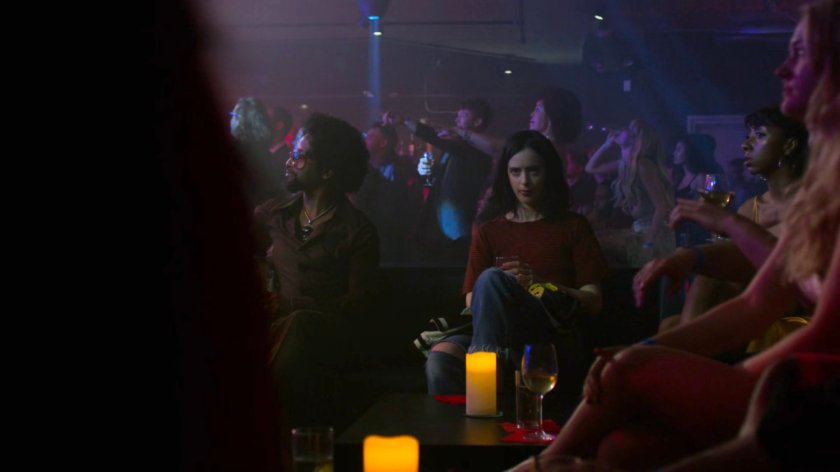 Jessica sitting in a dance club during Trish's single release party.