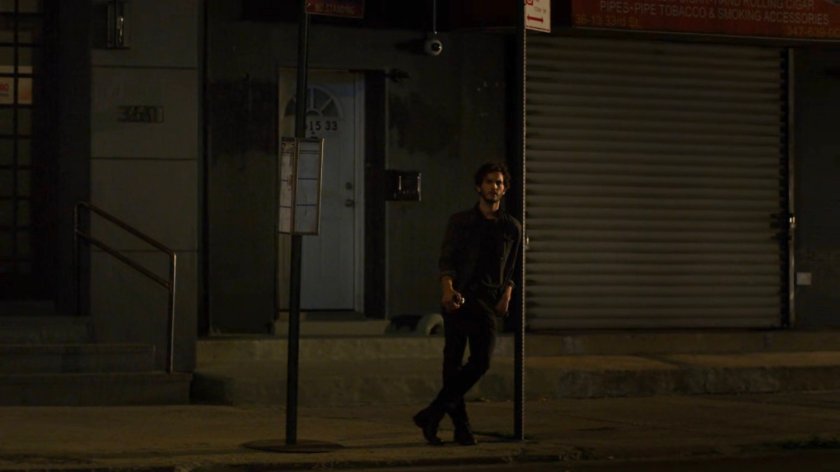 Stirling leaning against a traffic sign across from a dance club.