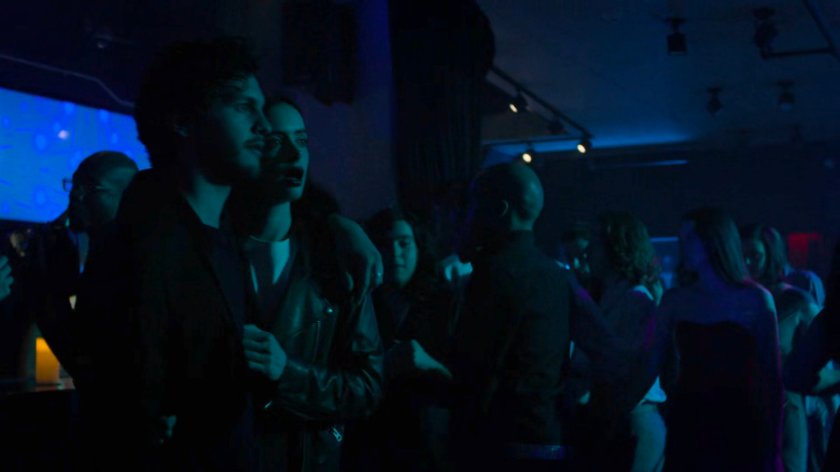 Stirling and Jessica walking through a crowded dance club.