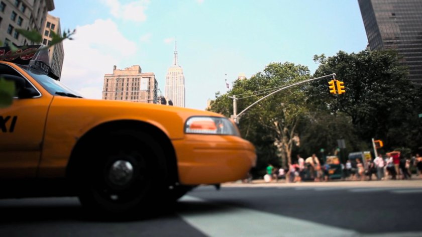 A cab in an intersection with the Empire State Building in background.