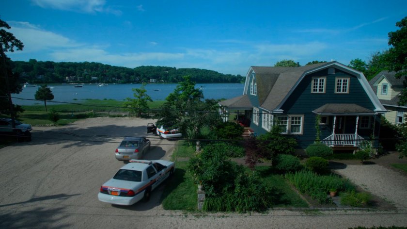 Exterior of Karl Malus's house with police cars arriving.