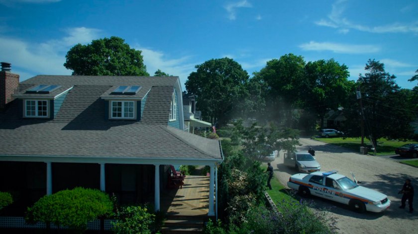 Exterior of Karl Malus's house with police cars arriving.