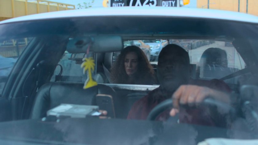 Jessica and Alisa in the back seat of a cab, while the driver looks at his phone.