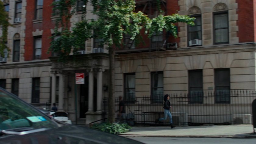 Jessica running along the sidewalk outside her apartment building.