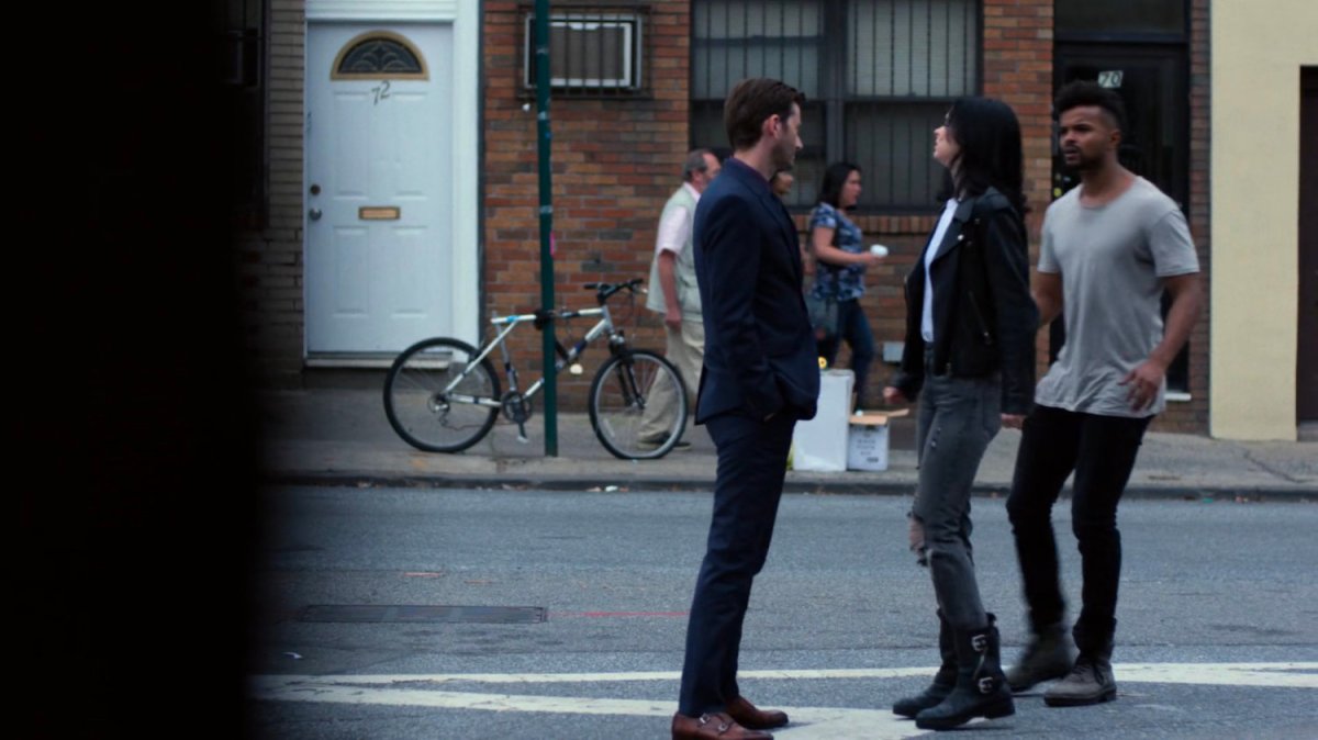 Kilgrave speaking with Malcolm and Jessica on the sidewalk.