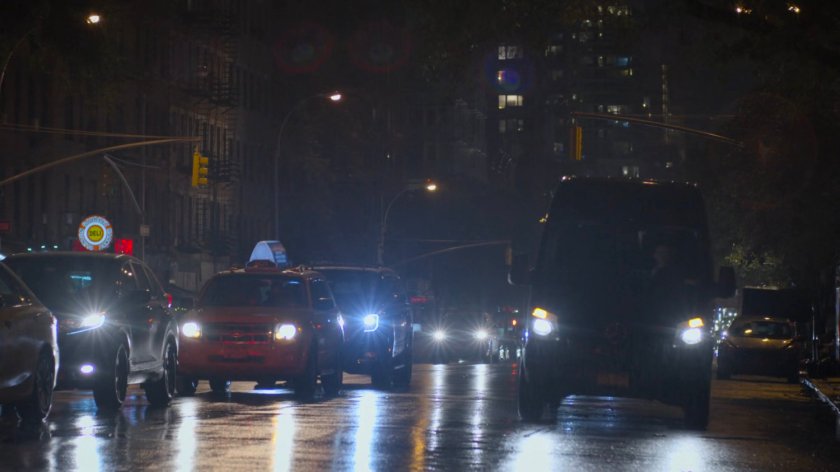 The mortuary van driving along a street at night.