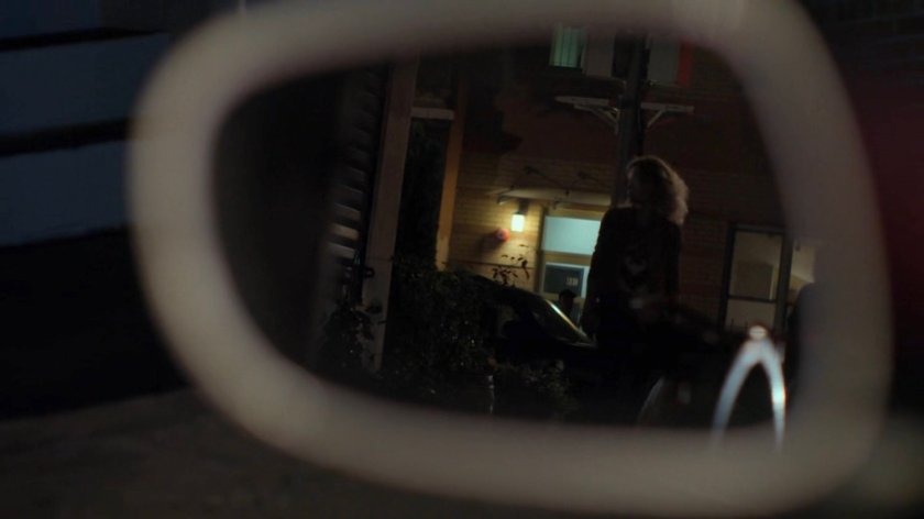 Inez reflected in Jeri's mirror outside Shane Ryback's house.