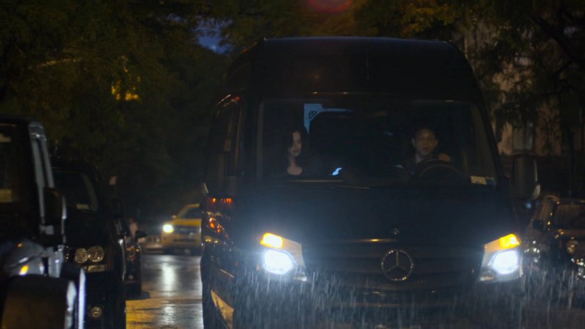 Jessica and driver pulling up outside Trish's apartment building in a mortuary van.