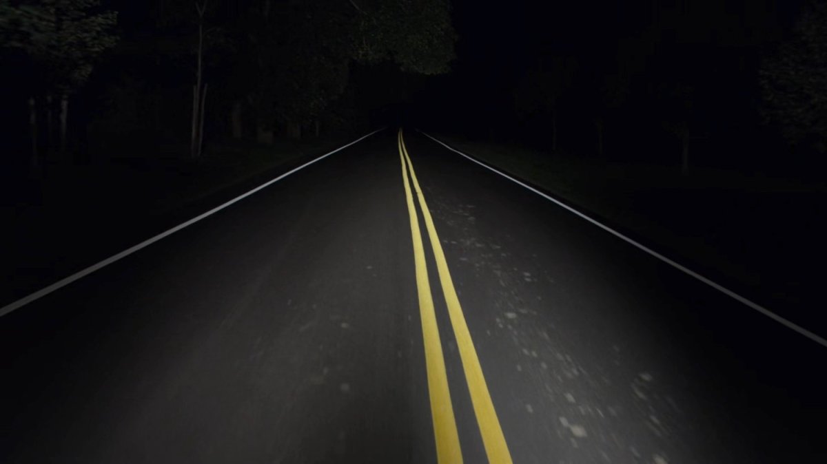 A road lit by headlights at night.