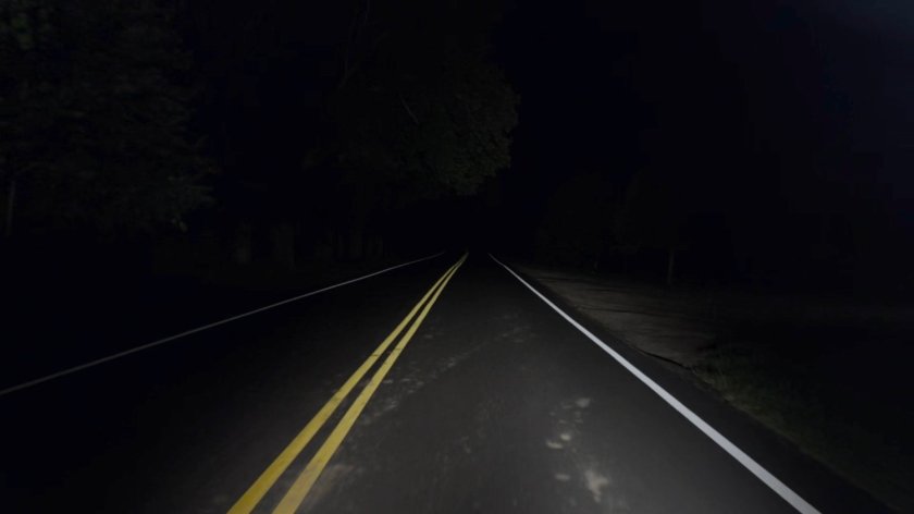 A road lit by headlights at night.