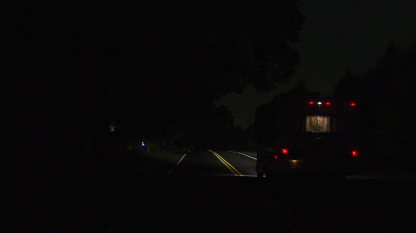 An RV on a road lit by headlights at night.