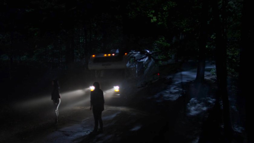 Jessica and Alisa on a dark road lit by RV headlights.
