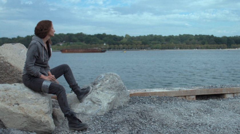 Alisa sitting on a rock at a gravel quarry.