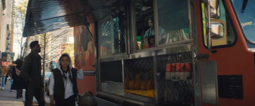 Angela walking away from the Arriba Arepas truck parked along a New York street.