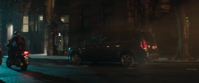 Dex driving a motorcycle away from his apartment building.