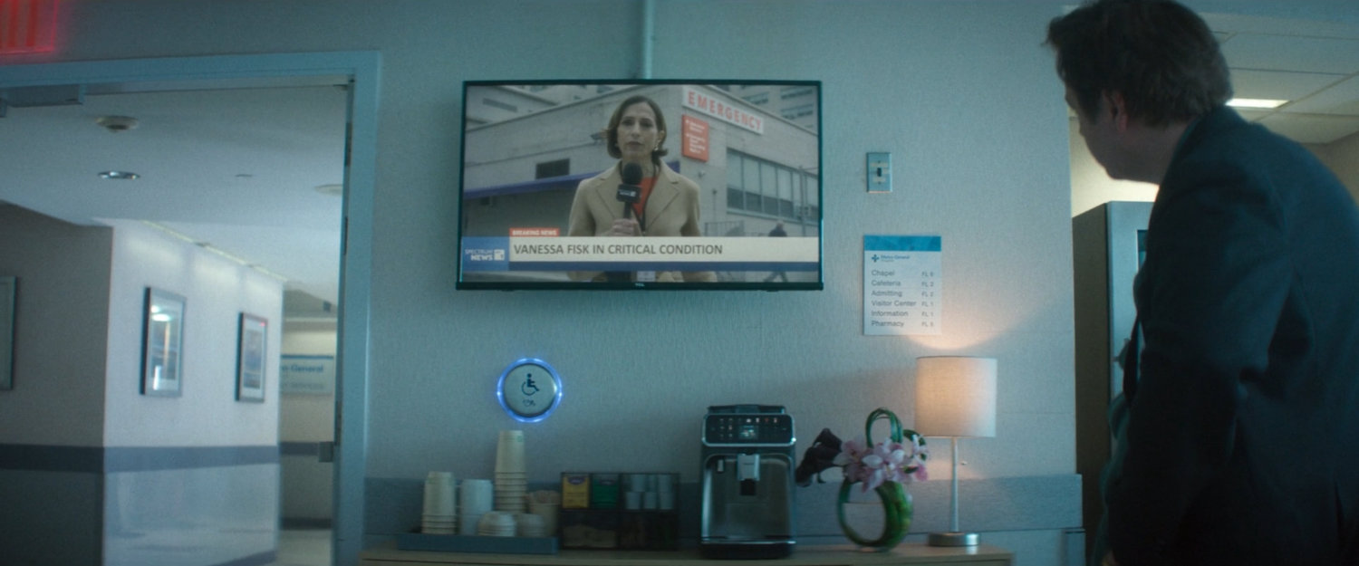 Daniel, inside the hospital, watching a news report from outside Metro-General.